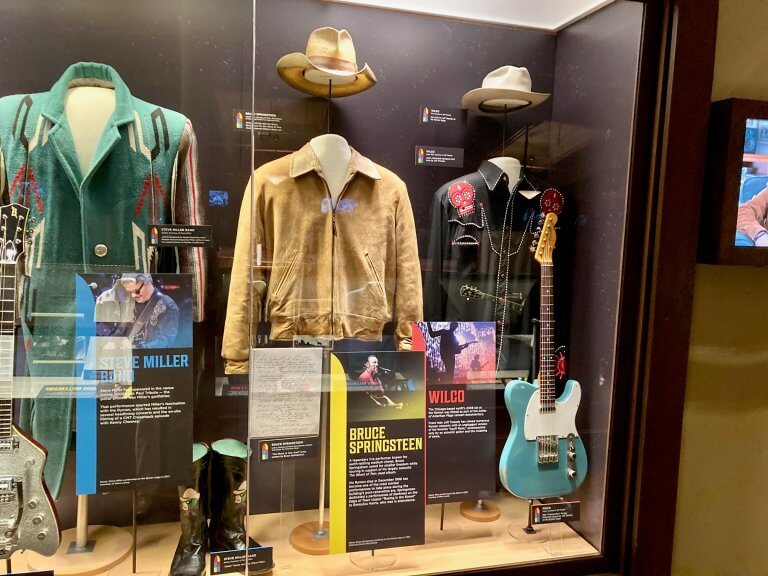 Display case of stage clothing and guitars, including a Bruce Springsteen jacket, in the Turn It Up! exhibit at the Ryman