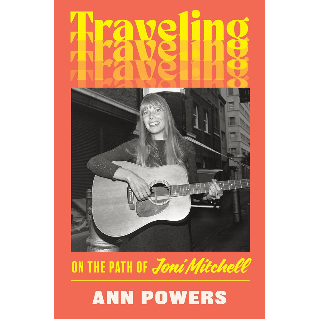 Cover of "Traveling On the Path of Joni Mitchell" by Ann Powers. Features a black and white photo of a smiling woman playing guitar on a city street. Bold yellow and white text on an orange background conveys a nostalgic tone.