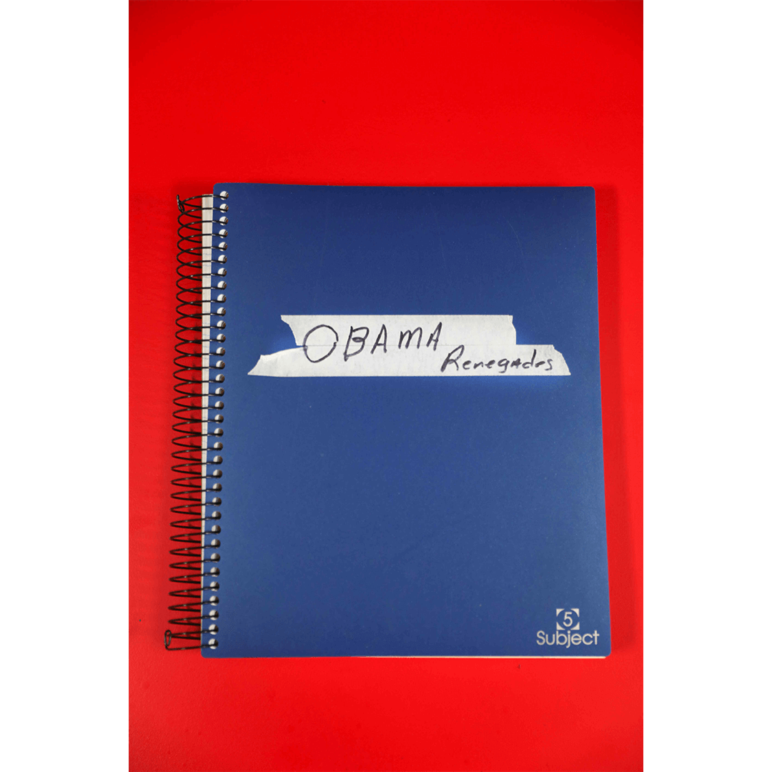 A blue spiral notebook against a red background has a piece of white tape labeled "OBAMA Renegades" in handwritten text near the top.
