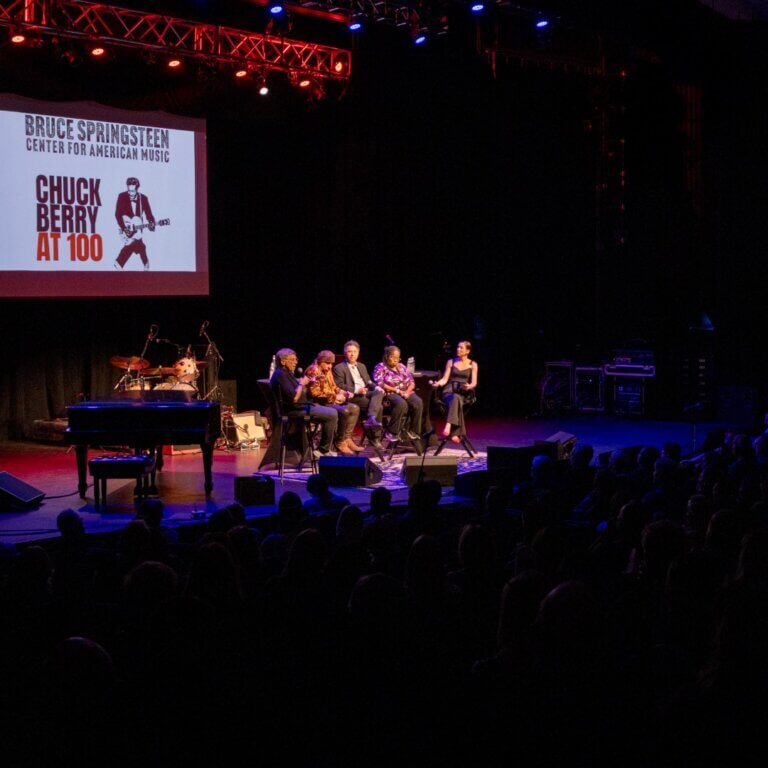 The Complicated Legacy of Chuck Berry panel on stage at Chuck Berry at 100, with Bob Santelli, Stevie Van Zandt, Alan Light, Hettie Williams and moderator Melissa Kozlowski seated beside a Chuck Berry at 100 screen